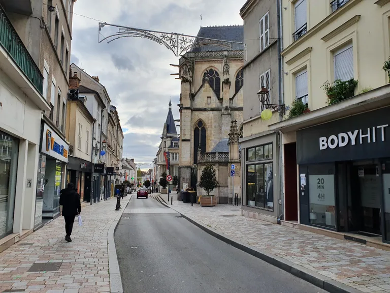 Rue Saint-Aspais à Melun, avec l’église et les façades des immeubles du centre ancien.