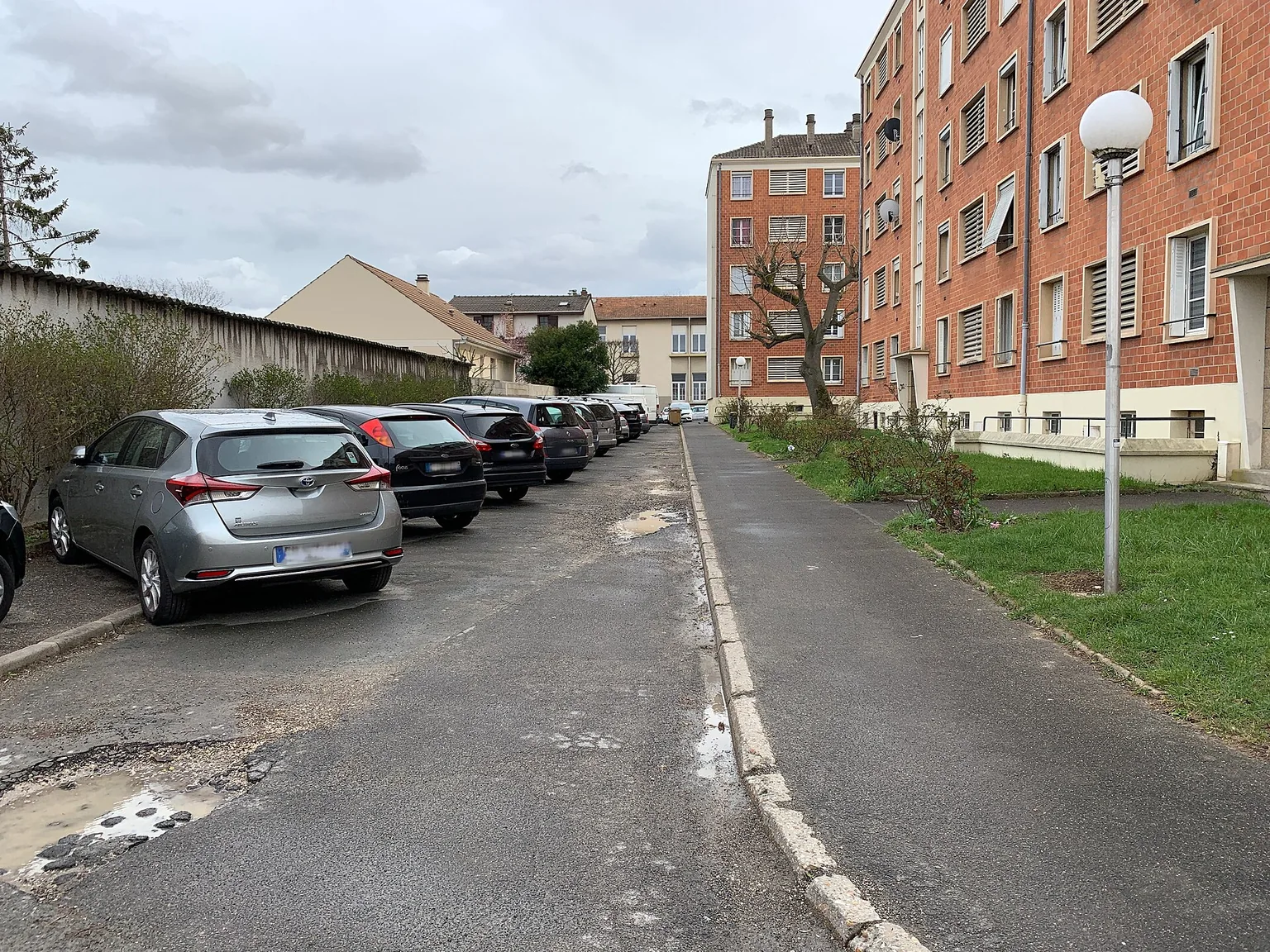 Allée Gustave-Courbet à Vitry-sur-Seine, avec bâtiments d’habitation en brique, cheminement et stationnements.